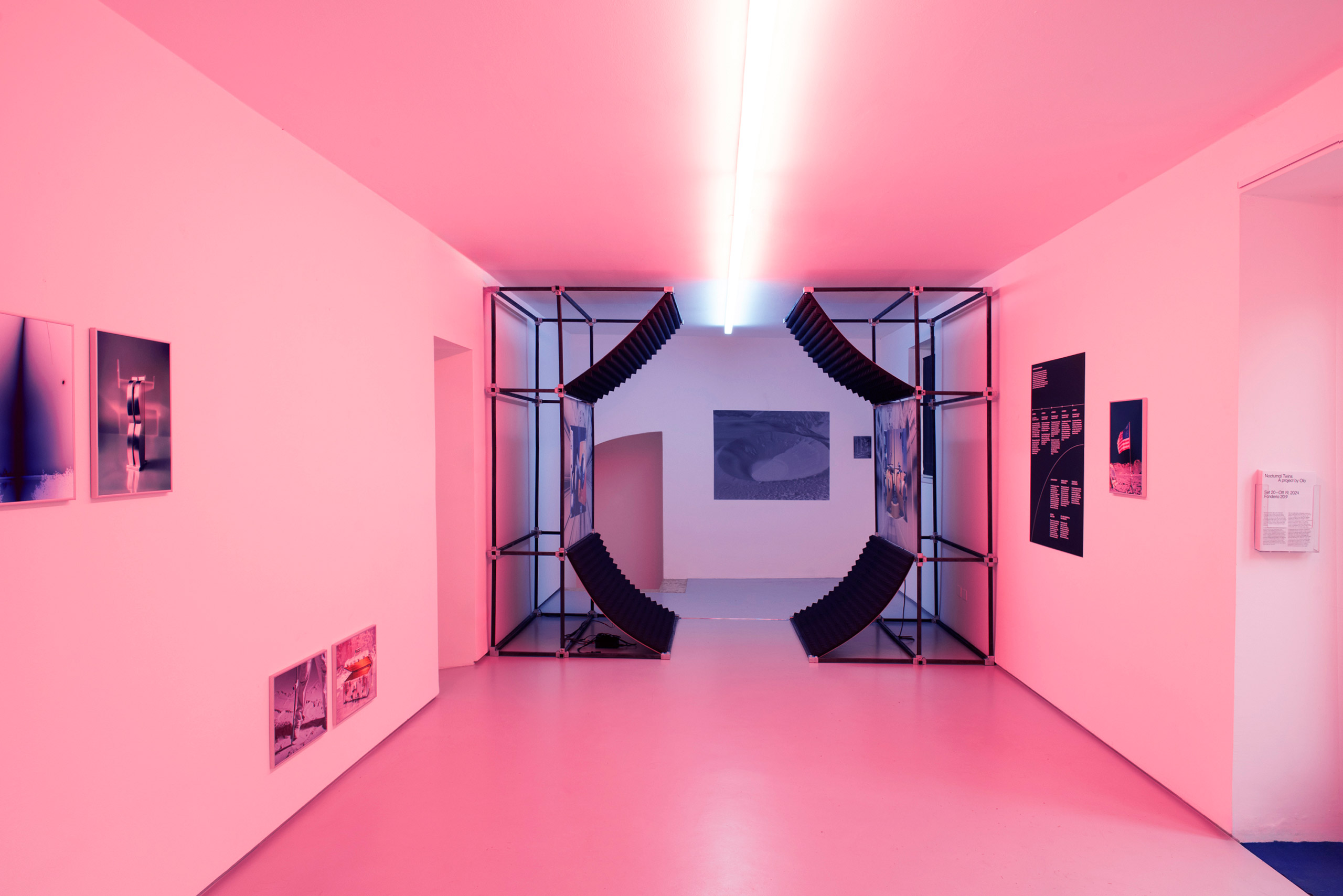 Interior of an exhibition with a metal installation and pink lights