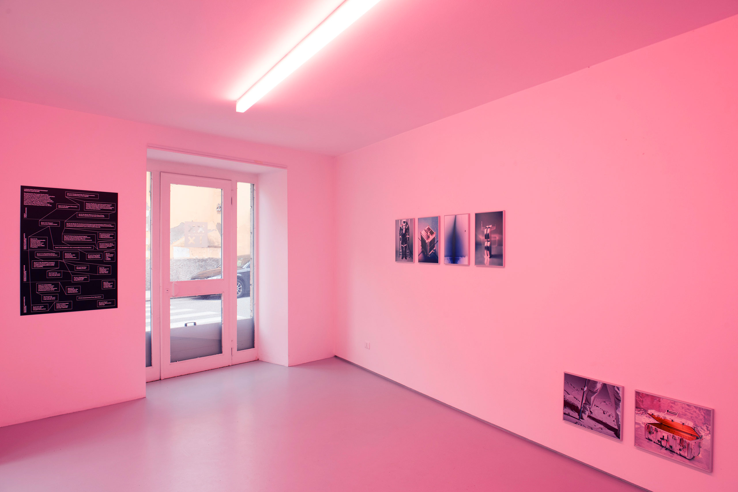 Interior of an exhibition with a window, photo, and pink lights