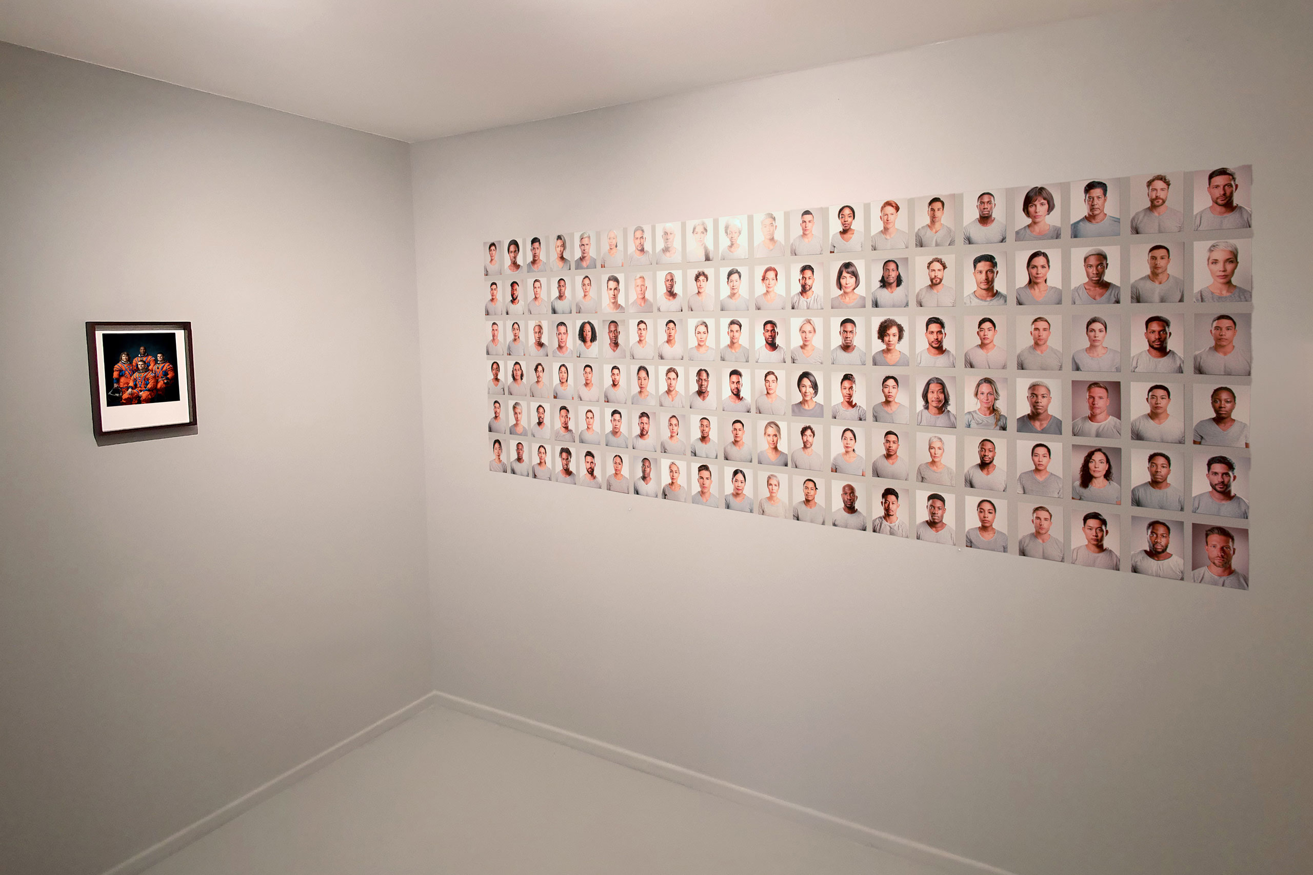 Corner of a room with photos hanging on the wall depicting human faces