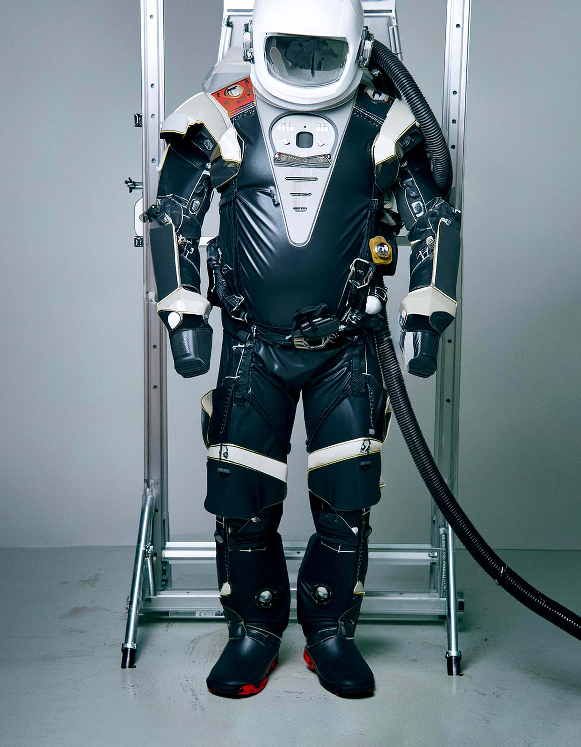 Black spacesuit with a white helmet hanging on a metal frame